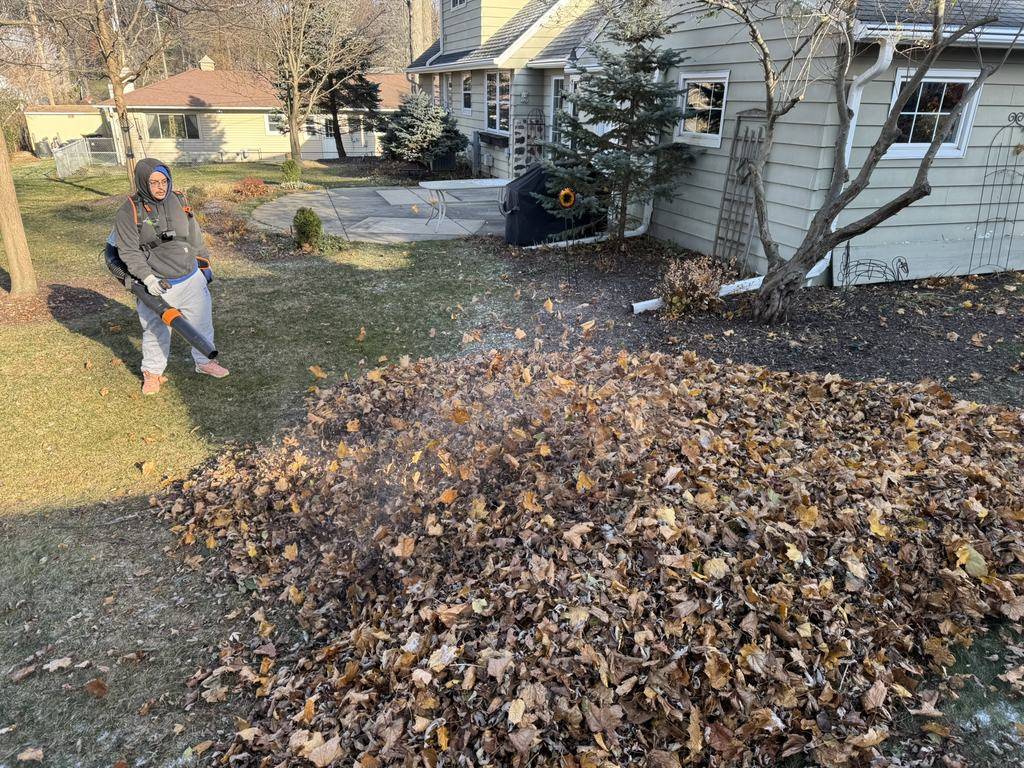 Loyal Landscaping crew member blowing leaves into a pile during a fall cleanup
