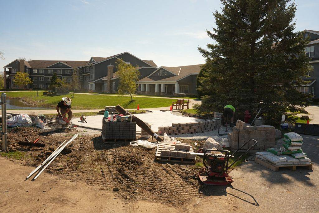 Loyal Landscaping crew cutting block and setting a seat wall around a new commercial paver patio