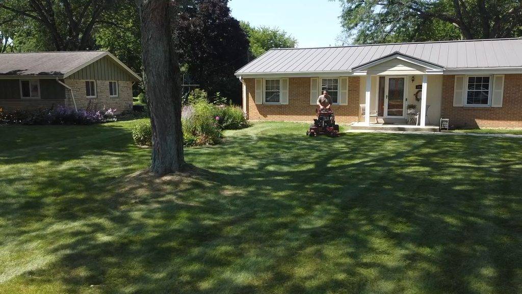 Loyal Landscaping crew member mowing a residential front lawn on a zero-turn mower