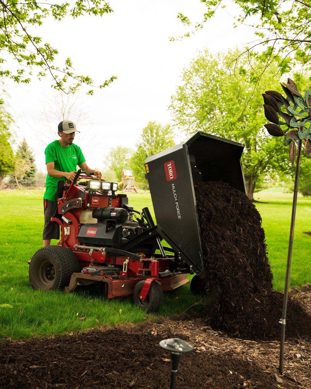 Loyal Landscaping crew member unloading fresh mulch from a Toro Mulch Force at a bed edge