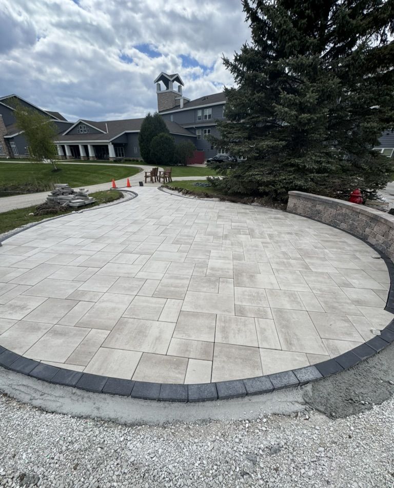 Finished large-format paver patio with a charcoal soldier-course border and curved seat wall