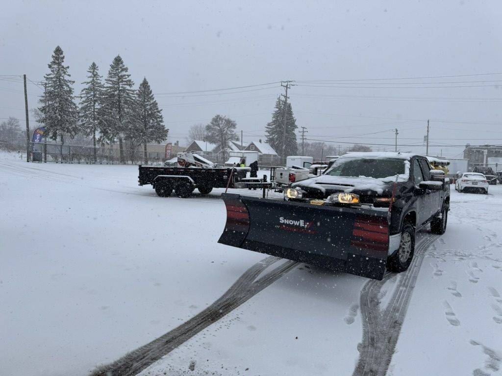 Loyal Landscaping plow truck and skid steer clearing a commercial lot during a Milwaukee snowfall